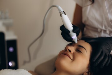Fototapeta premium Woman receiving modern facial skincare treatment in beauty salon. Facial hydropeeling