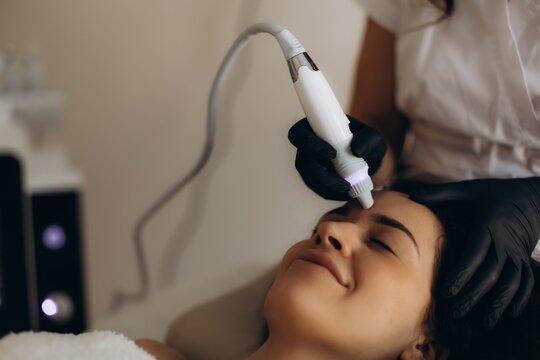 Woman receiving modern facial skincare treatment in beauty salon. Facial hydropeeling