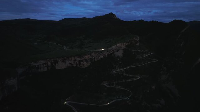 Drone footage of a serpentine mountain road with switchbacks along steep cliffs at blue hour near Keger village, Dagestan, Russia, dramatic travel landscape