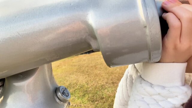  Main d'une petite fille ins&eacute;rant une pi&egrave;ce dans un t&eacute;lescope touristique public