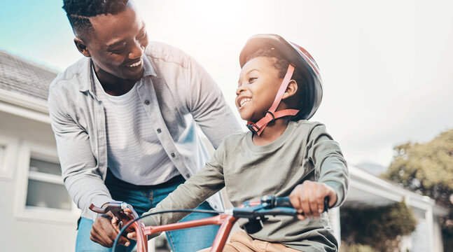 Balance, bicycle and smile of boy with dad on home driveway for bonding or child development. Black family, cycling and teaching son with single parent man outdoor for growth, learning or support