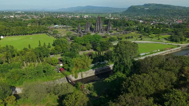Aerial view of the ancient Prambanan Temple complex surrounded by dense tropical trees and green lawns under a clear sky Kecamatan Prambanan, Daerah Istimewa Yogya, Indonesia.