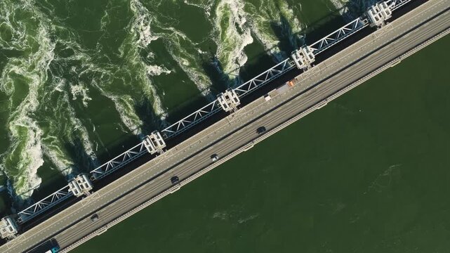 Aerial view of the Eastern Scheldt Storm Surge Barrier with cars driving across the bridge over turbulent green water in Vrouwenpolder, Zeeland, Netherlands.
