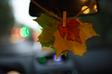 Fototapeta premium Autumn Leaf Hanging from Car Rearview Mirror - Colorful Fall Leaves Decor in Vehicle Interior