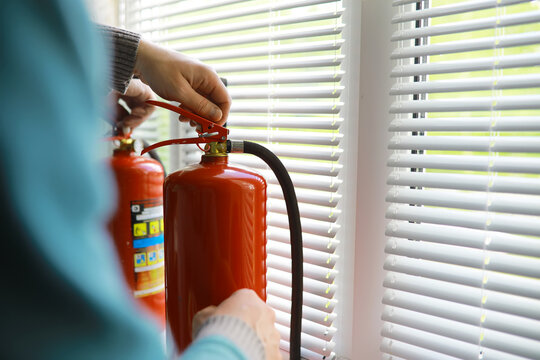hand presses the trigger fire extinguisher available in fire emergencies conflagration damage background. Safety