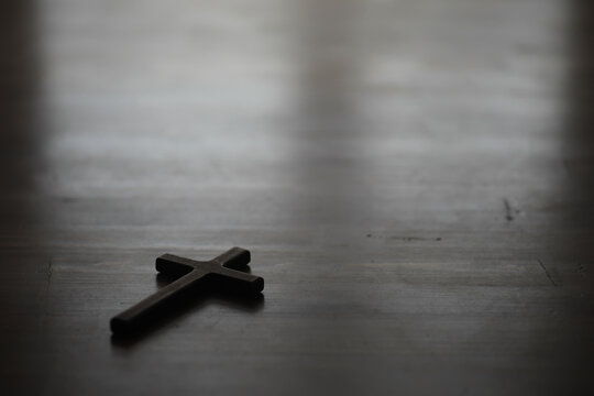 Wooden Cross on Dark Wooden Surface with Soft Light in Background for Spiritual and Religious Concepts