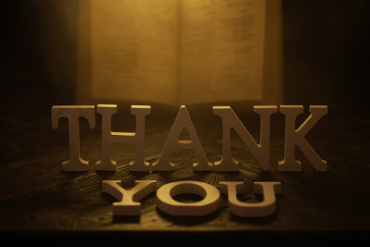 Thank You Message in Bold Wooden Letters with Warm Lighting and Book Background