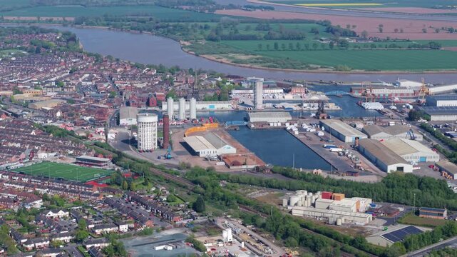 Aerial view of Goole Docks featuring industrial warehouses, shipping basins, and the River Ouse under a clear sky in Goole, England, United Kingdom.