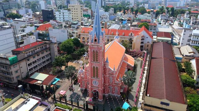 Aerial drone view of Tan Dinh Church in Ho Chi Minh City, Vietnam. Famous pink Catholic church surrounded by dense urban neighborhood, busy street and city buildings.