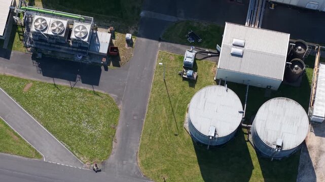 Aerial view of Guardian Glass Production Factory showing industrial tanks, cooling units and asphalt paths in Goole, England, United Kingdom.