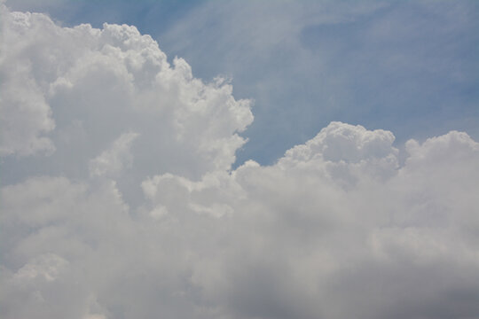 Dramatic white cumulus clouds against a bright blue summer sky.