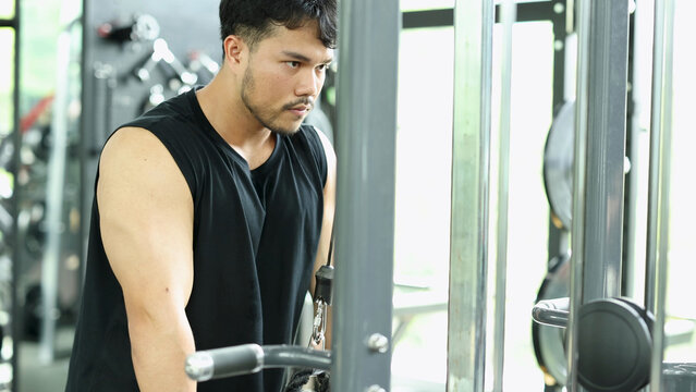 Focused Man Performing Triceps Cable Pushdown Exercise in Bangkok Gym