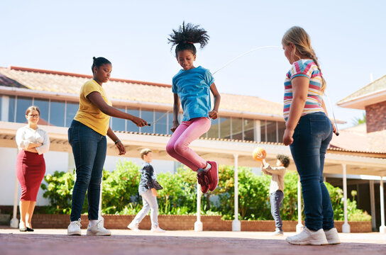 Break, rope and children jumping at school for learning recess, social development and supervision. Education, girl friends and skipping outdoor at montessori for playing, motor skills and activity
