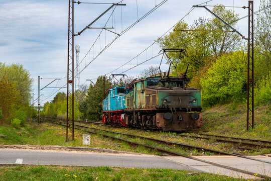 Industrial electric locomotive LEW EL2 Crocodile and blue train on mining railway line, historic brown coal transport train, overhead catenary system, industrial infrastructure, rolling stock of Konin