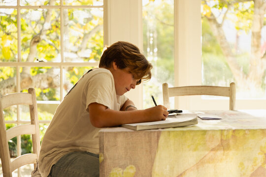 12 year old boy doing homework at kitchen table 