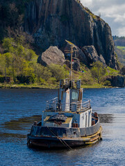 Fototapeta premium Old Boat in Dumbarton Harbour Scotland. Weathered Maritime Vessel and Calm Waterfront create scenic coastal heritage scene.