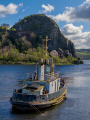 Fototapeta premium Old Boat in Dumbarton Harbour Scotland. Weathered Maritime Vessel and Calm Waterfront create scenic coastal heritage scene.