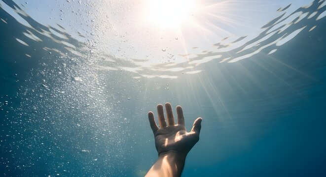 Hand reaching for sunlight from underwater. Survival and deep ocean rescue concept. Person stretching arm towards the surface surrounded by air bubbles.