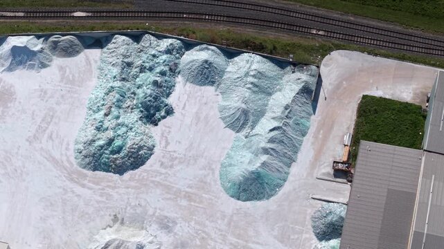 Aerial view of large piles of recycled glass cullet at the Guardian Glass Production Factory with nearby railway tracks in Goole, England, United Kingdom.