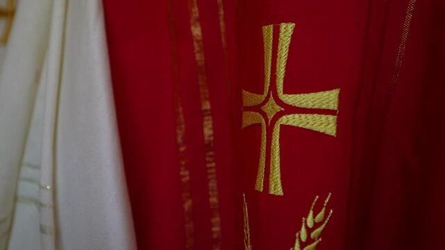 Golden cross embroidered on crimson velvet priestly robe for sacred church service