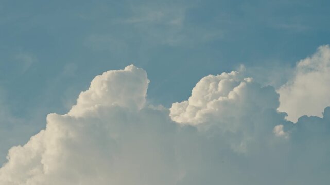 Close-up of soft, cotton-like cumulus clouds drifting across a vivid blue sky, creating a calm, airy atmosphere and a clean natural background.