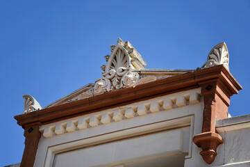 Ornate pediment and cornice on historic building facade under clear blue sky, heritage architecture © Magryt
