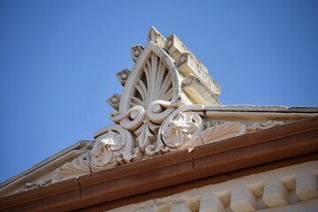Ornate pediment and cornice on historic building facade under clear blue sky, heritage architecture © Magryt