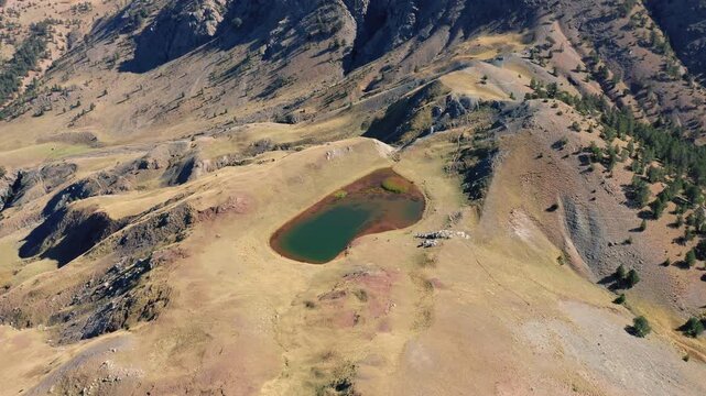 Slow panning drone shot of Drakolimni, Dragon Lake Smolikas on Mount Smolikas under a clear sunny sky
