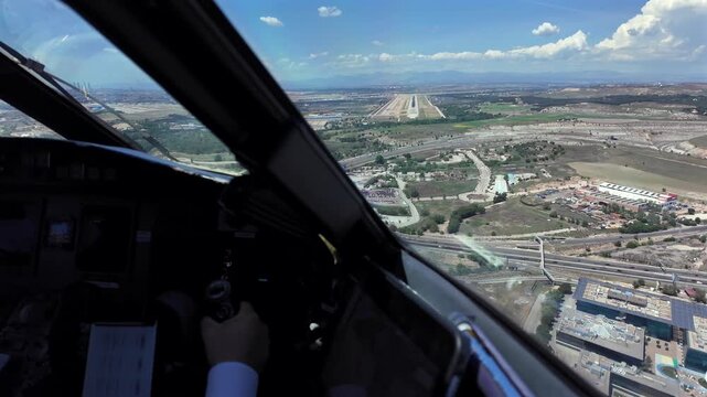 immersive pilot&rsquo;s eye view through the window of a jet airplane flying manually the flight controls with the rurway ahead, with a blue sky with few clouds.
