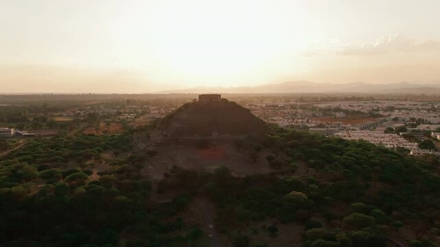 El Cerrito pyramid hill at sunset with warm light over Santiago de Quer&eacute;taro city, drone aerial view