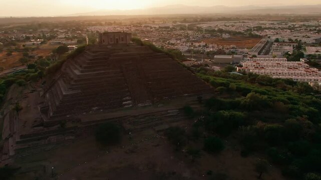 Aerial orbit of the ancient ruins at El Cerrito pyramid at sunset in Santiago de Queretaro, Mexico