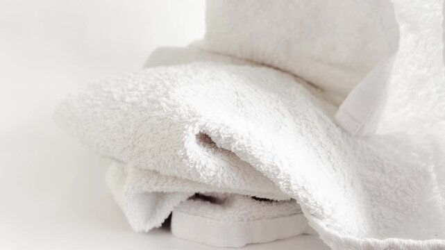 Fresh white towels, falling neatly to the floor with soft folds. Perfect for home bathroom, closet organization, laundromat or hotel textile care.