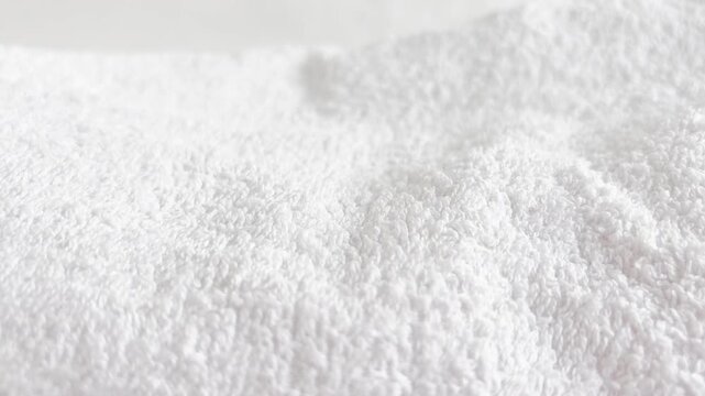 Slow motion macro shot of a white towel. Background with detailed pile of white towel. Texture of home textiles with fresh white towels.