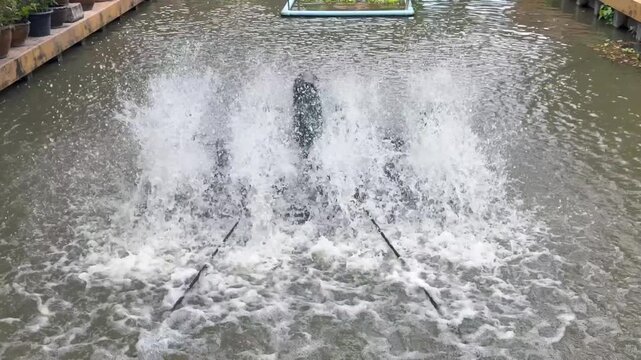 water turbine aerator splashing water in canal to increase oxygen. Wastewater treatment machine working in outdoor pond, sustainable agriculture and environmental technology in Thailand