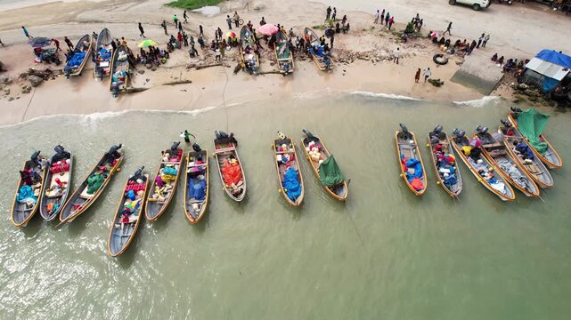Aerial view of numerous motorboats lined up on the sandy shore with people gathered at the water's edge in Wewak, East Sepik Province, Papua New Guinea.