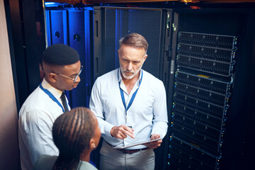 Cybersecurity, storage and tablet with team in data center together for problem solving or...