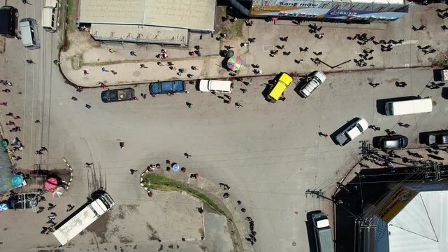 Aerial view of a busy street intersection with people walking and cars parked near buildings in Wewak, East Sepik Province, Papua New Guinea.