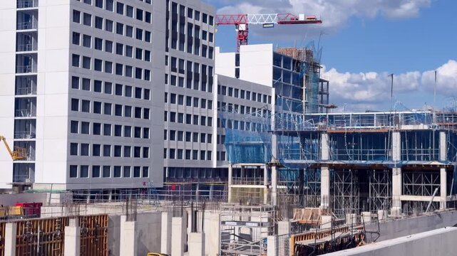Madrid, Spain - May 4, 2026: Modern residential and commercial buildings under construction at a large Dragados development site with cranes, scaffolding and reinforced concrete structures in Valdebeb