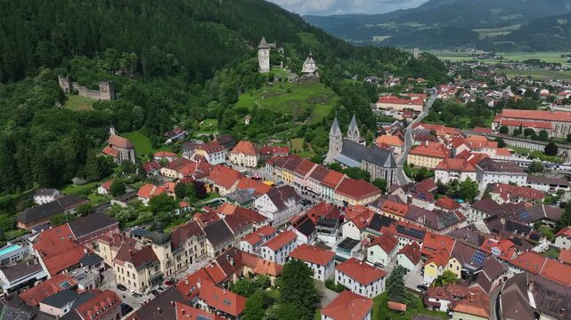 Summer drone footage showing medieval Friesach, old fortified walls, rooftops, towers, hills, serene atmosphere, warm daylight, gentle cinematic motion