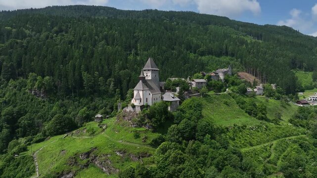 Summer drone footage showing medieval Friesach, old fortified walls, rooftops, towers, hills, serene atmosphere, warm daylight, gentle cinematic motion