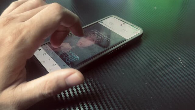 Hand Scrolling on Smartphone Screen Over Carbon Fiber Texture
