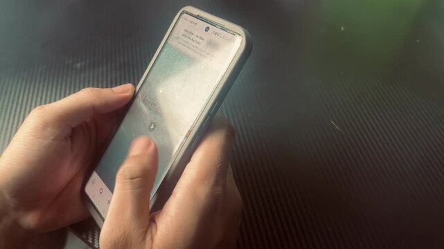 Hand Scrolling on Smartphone Screen Over Carbon Fiber Texture
