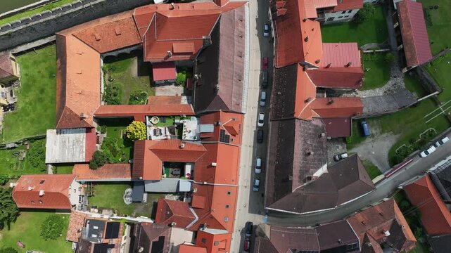 Summer drone footage showing medieval Friesach, old fortified walls, rooftops, towers, hills, serene atmosphere, warm daylight, gentle cinematic motion