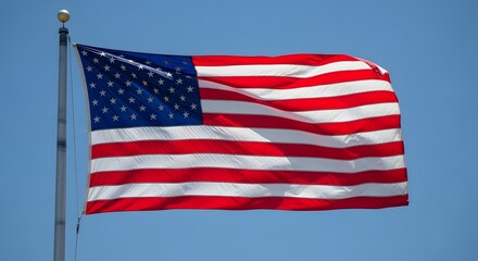 Fototapeta premium American flag waving on a flagpole against a clear blue sky