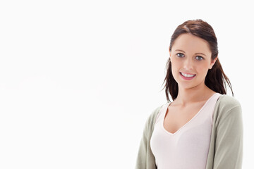 Fototapeta premium Woman in 20s posing at right of white backdrop, wearing pink camisole and cardigan, copy space