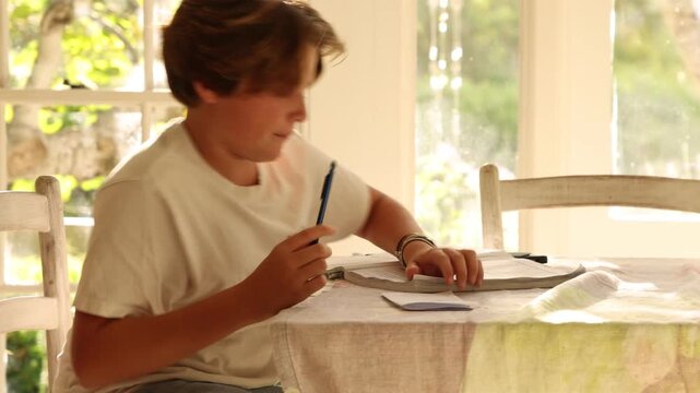 12 year old boy doing homework at kitchen table  at sunset