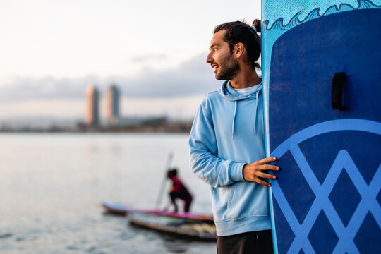 Happy fit man paddle surfing, enjoying vacation, weekend to stay healthy