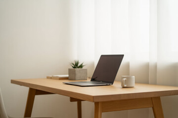 Fototapeta premium Modern home office, wooden desk with laptop, plant, and coffee cup, minimalist workspace