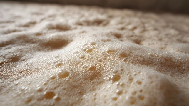 ro close up view of delicate creamy soap suds bubbles resting on a wet pale textured surface