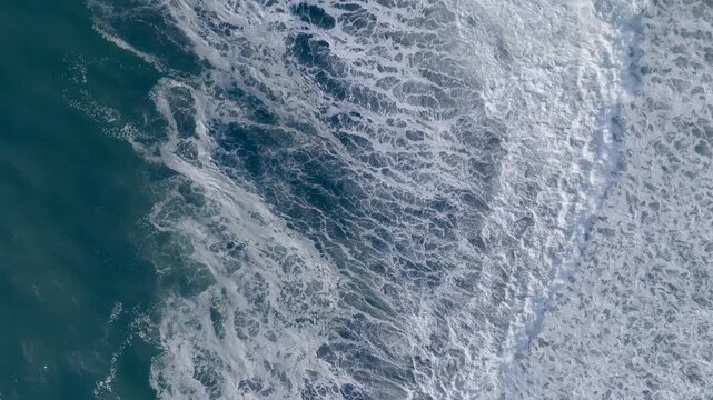 Top down aerial view of ocean surf and sea foam rolling onto Khalaktyrsky Beach, Kamchatka Krai, Russia, natural seascape background with copy space